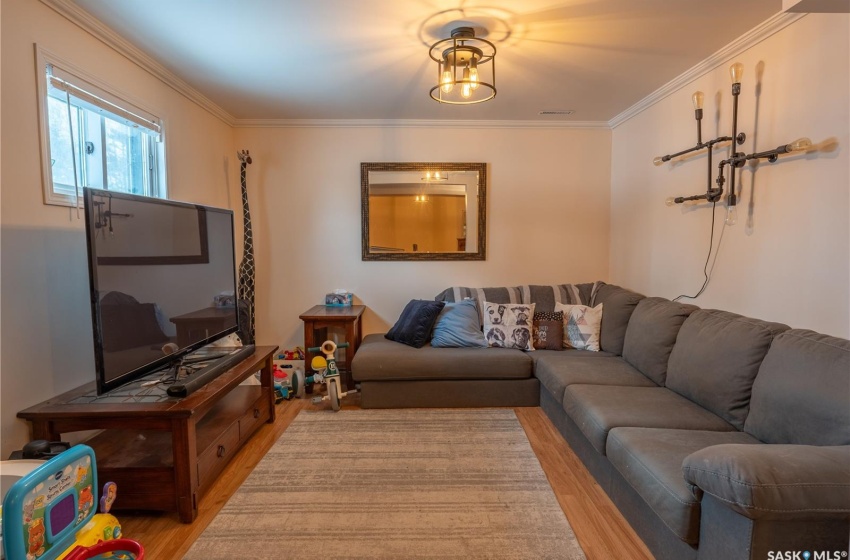 Living room with light wood-type flooring and crown molding