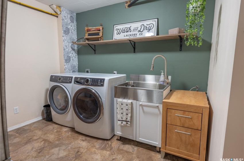 Clothes washing area featuring laundry area, baseboards, separate washer and dryer, and a sink