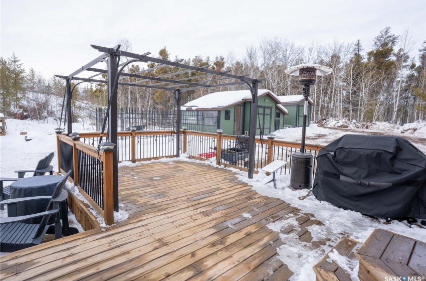 Snow covered deck with an outdoor structure, grilling area, a storage shed, and fence