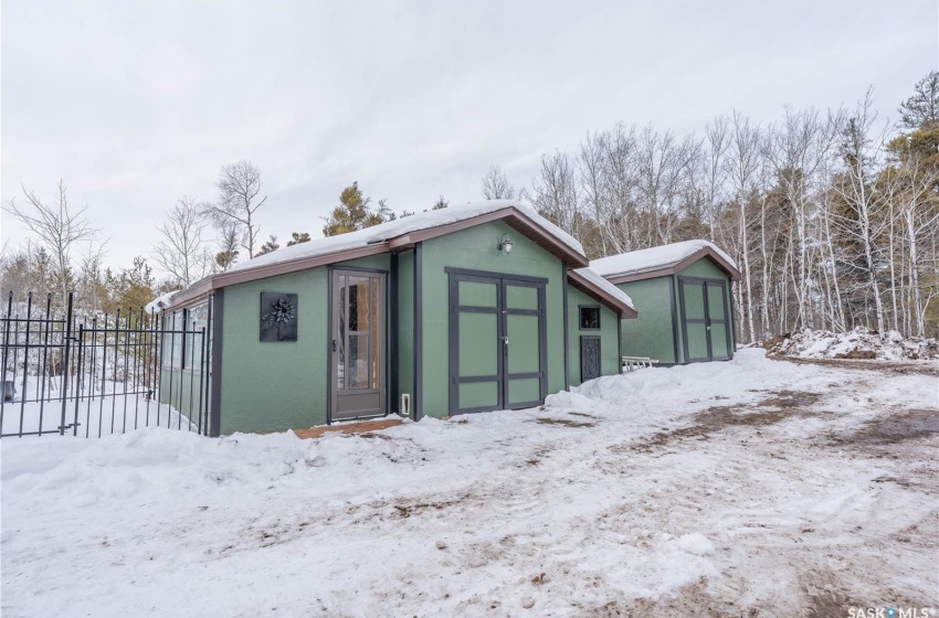 Snow covered structure with a storage unit, an outdoor structure, and fence