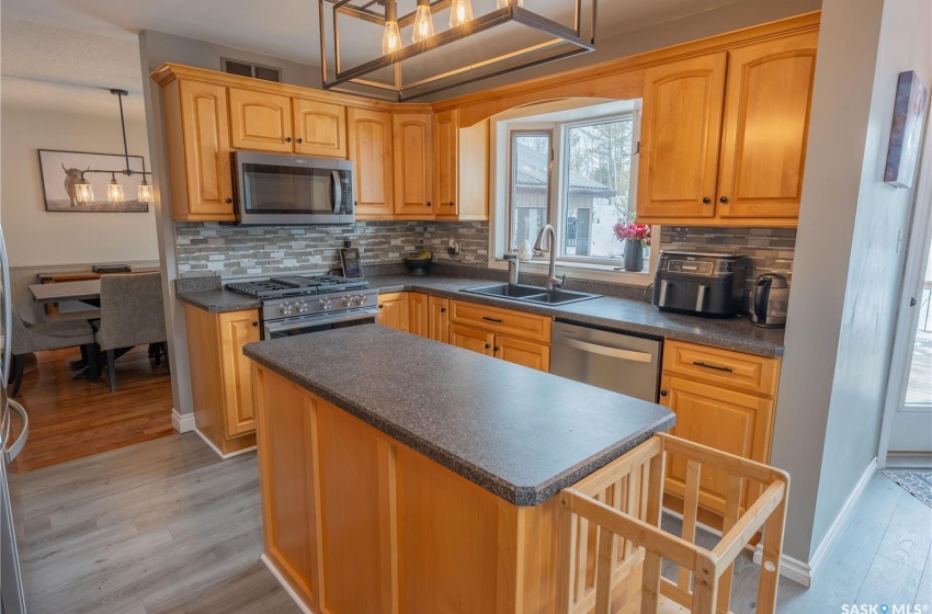 Kitchen featuring appliances with stainless steel finishes, dark countertops, pendant lighting, and a sink