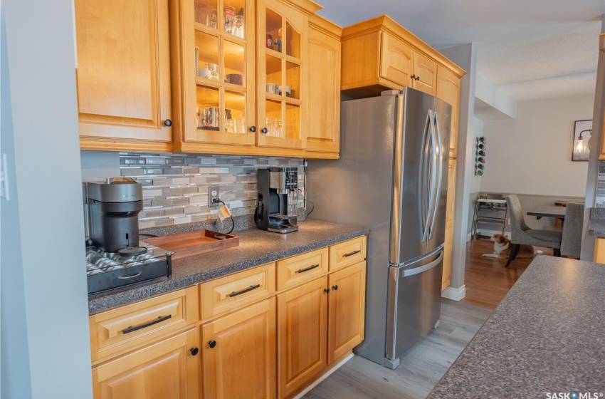 Kitchen featuring dark countertops, glass insert cabinets, and freestanding refrigerator