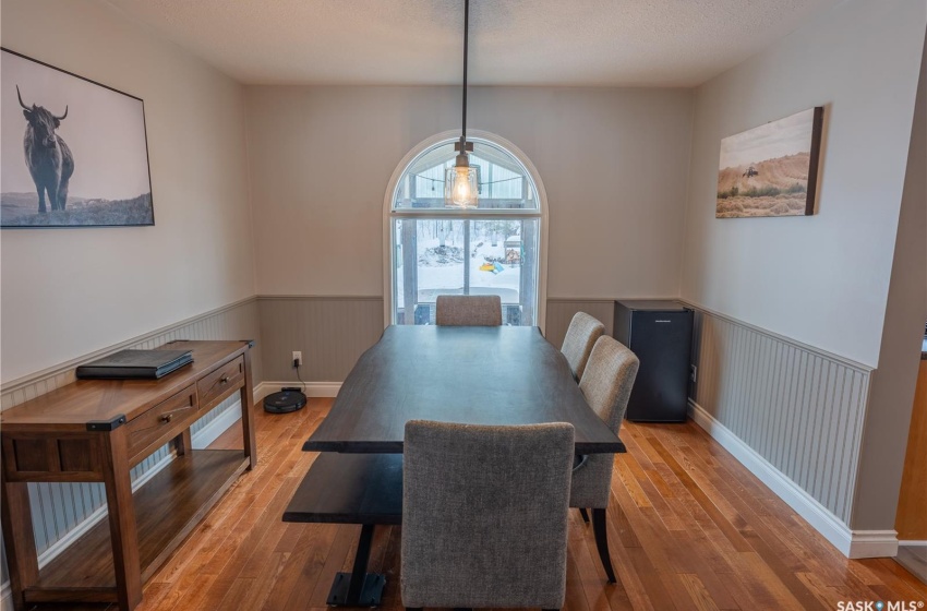 Dining room with a wainscoted wall, a textured ceiling, and wood finished floors