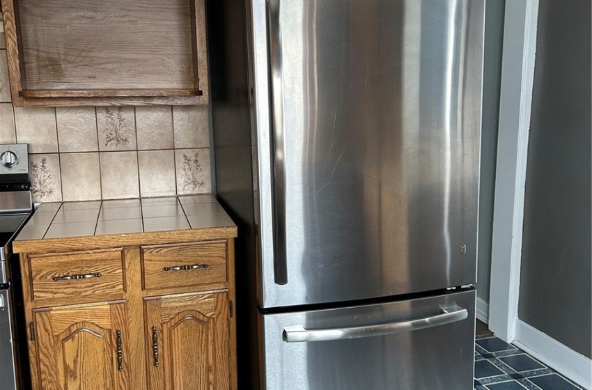 Kitchen featuring brown cabinetry, range, and freestanding refrigerator