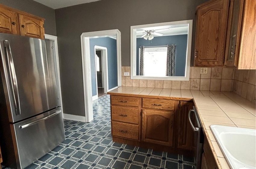 Kitchen with tile countertops, tasteful backsplash, and refrigerator