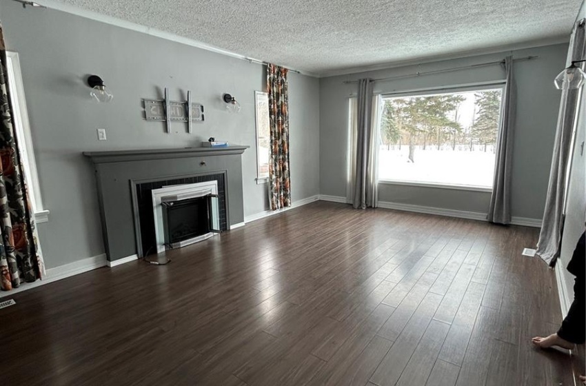 Unfurnished living room with a textured ceiling, a fireplace, and dark wood-style flooring