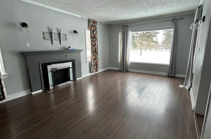 Unfurnished living room with a textured ceiling, dark wood-style flooring, and a fireplace