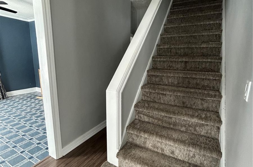 Stairs featuring a textured ceiling, baseboards, and wood finished floors