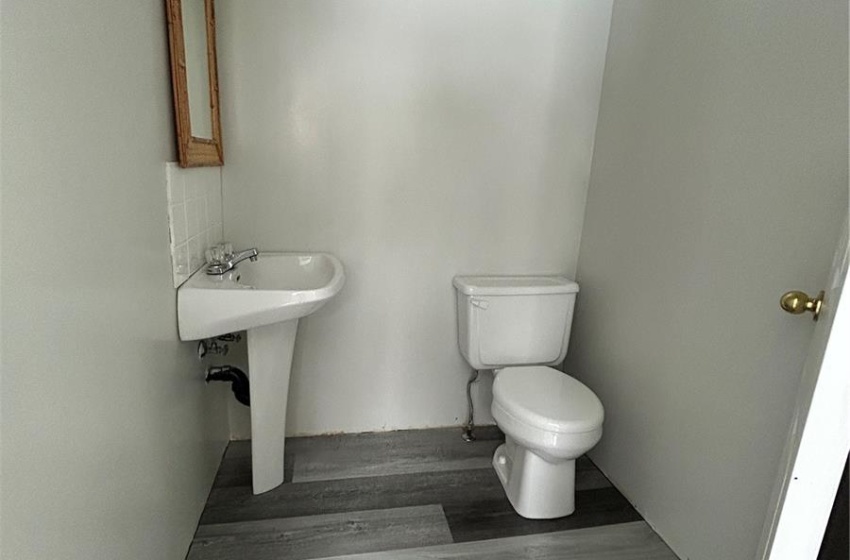 Half bathroom featuring a sink, toilet, and wood finished floors