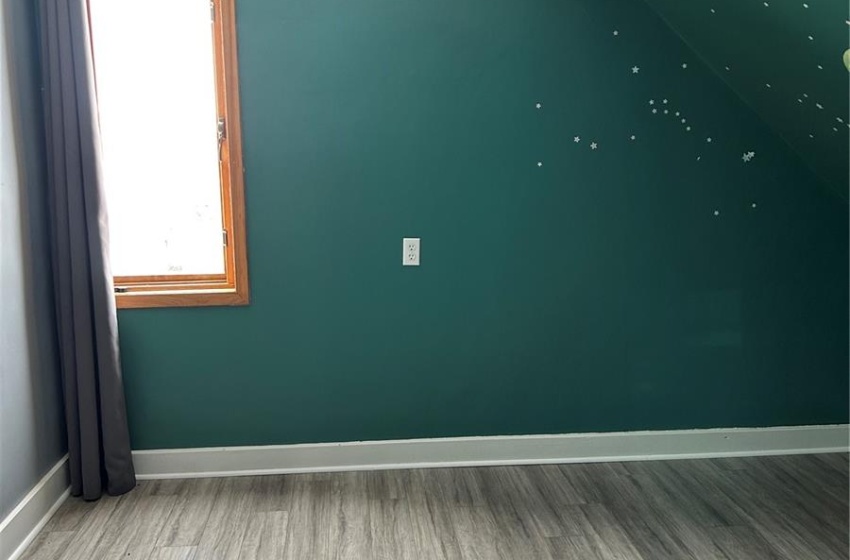 Unfurnished room featuring lofted ceiling, a textured ceiling, baseboards, and wood finished floors