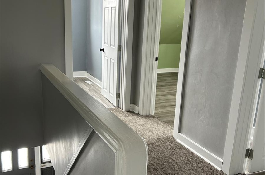 Hallway with baseboards, carpet flooring, and wood finished floors