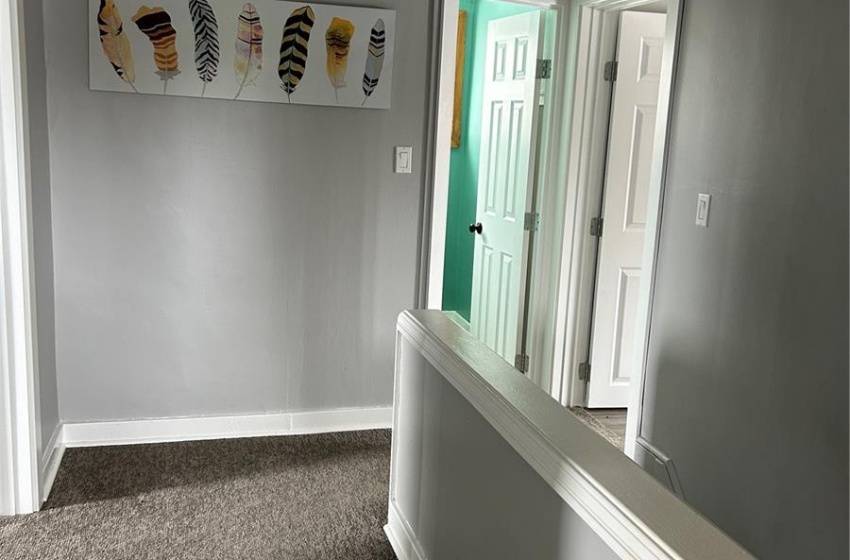 Hallway with dark carpet, a textured ceiling, and baseboards