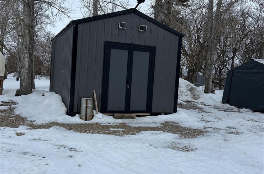 Snow covered structure featuring an outbuilding and a storage unit