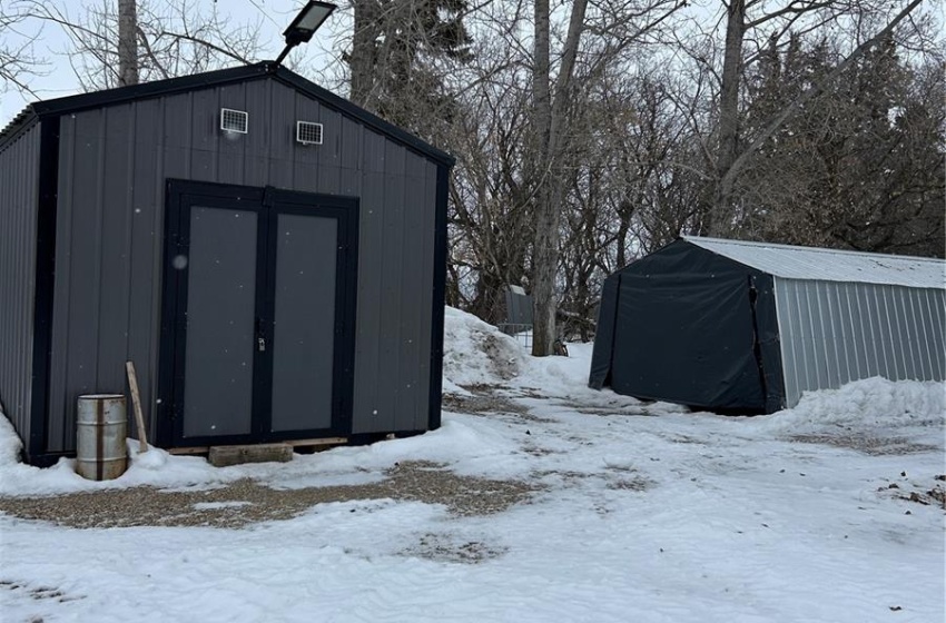 Snow covered structure with a storage shed and an outbuilding