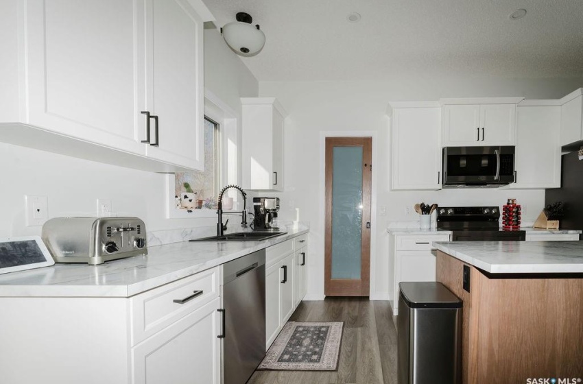 Kitchen with sink, appliances with stainless steel finishes, and white cabinetry