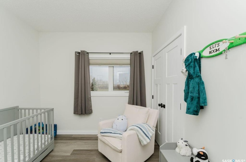 Bedroom with a textured ceiling, hardwood / wood-style floors, and a nursery area