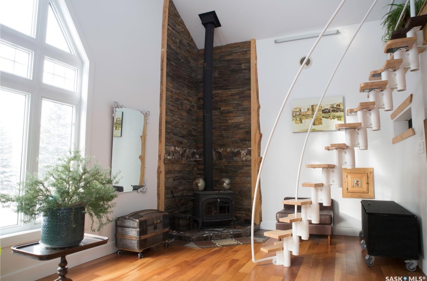 Living room with a wood stove, a high ceiling, and wood finished floors