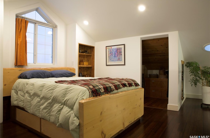 Bedroom featuring vaulted ceiling, multiple windows, wood finished floors, and baseboards