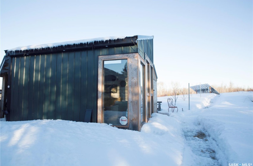 Snow covered structure featuring an outbuilding